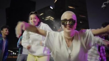 Kentteki parti gecesinde dans eden gençler. Modern çok kültürlü arkadaşlar birlikte müzikten zevk alıyorlar. Yüksek kalite fotoğraf