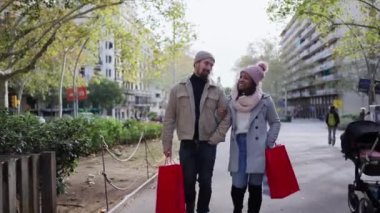 Güzel, genç ve ırklar arası bir çift şehrin sokaklarında kış tatilinin tadını çıkarıyor, yürüyüş yapıyor, hediye çantalarını tutuyor ve dışarıda Noel 'i kutluyorlar.