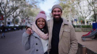 Dışarıda çok ırklı mutlu bir çiftin portresi. Genç bir kadın ve aşık bir adam Noel zamanı arka sokaktaki kameraya sarılıp gülümsüyor. İnsanlar kış kıyafetleri giyiyordu.