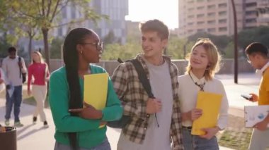Üniversite kampüsünde yürüyen, gülümseyen ve mutlu bir şekilde kameraya bakan bir grup çok ırklı genç öğrenci. Yaşam Tarzı Z Arkadaşları dışarıda eğleniyor. Uluslararası insanlar günlük yaşam