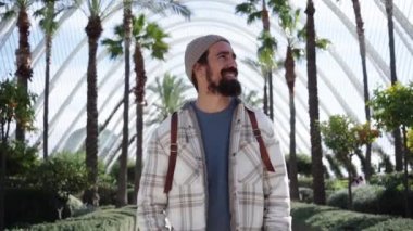 Valencia bilim parkında gülümseyen yakışıklı beyaz adam. Neşeli genç turist güneşli kış gününde canlı yürüyor. Erkek etrafa mutlu mesut bakıyor. Bin yıllık kuşağın kültür turizmi.