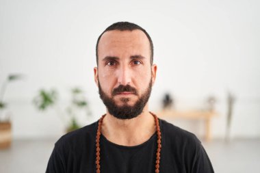 Kameraya bakan sakallı, beyaz bir adamın yakın çekimi. Orta yaşlı bir adamın portresi. Japon Mala kolyesiyle içeride konsantre oluyor. Erkek sağlığı, vücut bakımı, yoga ve akıl sağlığı kavramı.