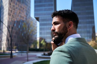 Genç yakışıklı beyaz iş adamı telefonda ciddi bir ifadeyle konuşuyor. Takım elbiseli profesyonel bir erkek dışarıda gezintiye çıkıyor. Binaların geçmişine sahip başarılı bir işçi..