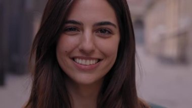 Kapalı portre neşe dolu genç beyaz kadın şehir caddesinde gülümsüyor. Açık havada kameraya bakan güzel yüzlü kadınlar. Dışarıdaki resim için poz veren İspanyol kız.