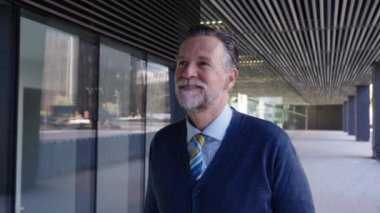 Portre, beyaz saçlı, neşeli, beyaz saçlı bir işadamı dışarıda dolaşırken mutlu bir ifade takınıyor. Finans adamı ofis dışında gülümsüyor. Üst düzey profesyonel kameraya bakıyor.
