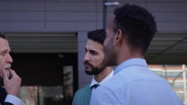 Üç farklı ciddi iş adamı dışarıda iletişim kuruyor. Takım elbiseli iş arkadaşları ofis dışında birlikte dolaşmaktan endişe duyuyorlar. Profesyonel insanlar ve iş ilişkileri.