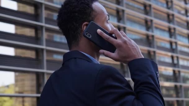 特写镜头下英俊的非洲裔美国商人在办公室外严肃地在手机上安静地走着 人们穿的职业装都是用手机 年轻的黑人企业家在休息工作 — 图库视频影像