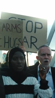 Dikey video. Dünyadaki savaş ve şiddeti protesto eden çeşitli insanlar. Barış ve insan hakları gösterilerinde savaş karşıtı pankartlara sahip bir grup aktivist. 