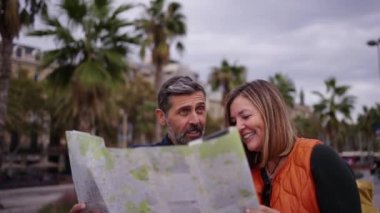 Orta yaşlı Kafkasyalı çift ellerinde seyahat haritası ile turistlerin ilgisini çeken yerleri gösteriyorlar. Şehirdeki karı koca tatilin tadını çıkarıyor ve gülüyorlar. Yetişkin turizm insanları 