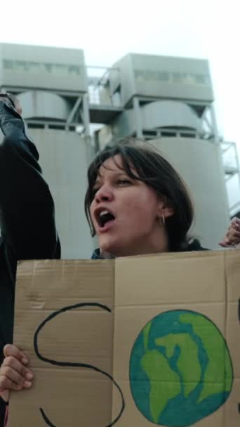地球温暖化のための怒りに満ちた屋外で叫ぶ人々の垂直なグループ 気候変動のためのバナーとの地球のプロデュース コミュニティの汚染に対する抗議で女性に焦点を当てる — ストック動画