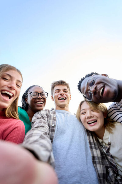 Vertical selfie Portrait large group multiracial friends posing smiling and looking to camera. Happy young people hugging together standing outdoors. Gen z guys and girls enjoying spring vacation day