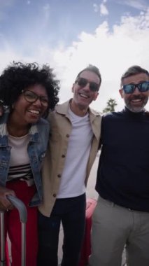 Dikey grup orta yaşlı turist arkadaşları birbirlerine sarılmış ve kameraya bakıp birlikte gülerek tatilin tadını çıkarıyorlardı. Çeşitli turistlerin bavulları güneşli bir günde şehir caddesinde eğleniyor.