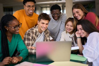 Kampüsteki kafeteryada sınıf arkadaşları bir projede çalışırken dizüstü bilgisayar kullanan neşeli genç bir üniversite öğrencisi grubu. Fakülte binasında birlikte çalışan çok kültürlü insanlar.