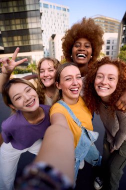 Açık havada gülümseyen çok kültürlü genç kız arkadaşlar. Neşeli insanlar mutlu poz veriyor. Gezici fotoğraflara sarılıyorlar. Birlikte kameraya bakıyoruz. Sadece feminist kadın topluluğu
