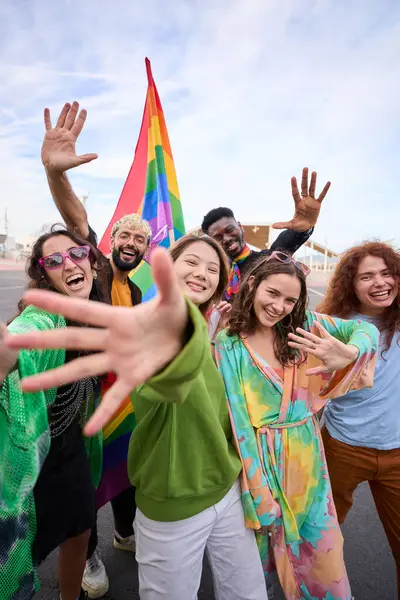 Vertical crowd of happy people in colorful wear smile for a selfie with a rainbow flag, capturing their fun and leisurely travel recreation in the pride day. LGBT diverse people united for community