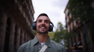Kablosuz kulaklıklı genç Kafkasyalı turist Avrupa 'nın Paris şehrinde sokakta müzik dinlemekten zevk alıyor. Mutlu milenyum erkekleri neşeli doğa gezisi turizmi