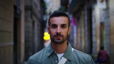 Avrupa 'nın Barcelona şehrindeki caddede kameraya ciddi ciddi bakan sakallı, yakışıklı bir adam görülüyor. Kafkasyalı erkek turist, gece turizmi için ciddi poz veriyor.