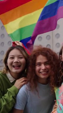 Gökkuşağı bayrağıyla dikey selfie çektirmek için renkli tebessümlü mutlu insanlardan oluşan bir kalabalık onların eğlencesini ve eğlencelerini yakalıyor. Gay ve lezbiyen arkadaşlar LGBT 'nin gay onur yürüyüşü konseptinde birlikteler