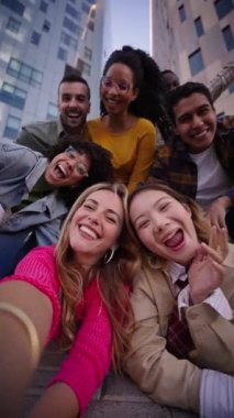 Dikey. Bir grup mutlu insan eğlenceli bir anı paylaşıyorlar. Genç arkadaşlar boş zamanlarında selfie çekiyorlar. Ekip birlikte seyahat ediyor. Kameraya bakarak gülümseyen topluluk portresi