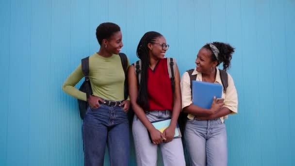 Три Улыбающиеся Чернокожие Ученицы Стоящие Папками Радостно Смотрят Друг Друга — стоковое видео