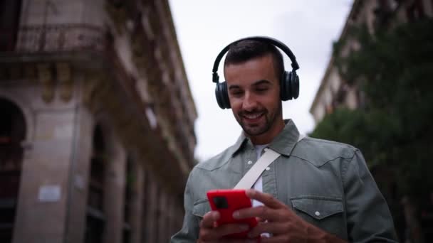 Młody Atrakcyjny Mężczyzna Słuchawkami Spaceruje Lubi Słuchać Muzyki Kiwając Głową — Wideo stockowe