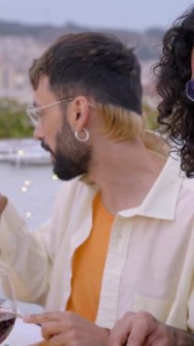 Dikey. Dışarıda birlikte yemek yiyen çok ırklı bir grup genç arkadaş. Neşeli insanlar çatıda barbekü partisi için toplandılar. Milenyum nesli ve arkadaşlık kavramı. 