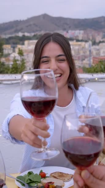 垂直に 屋上のテラスでBbqディナーを祝うために陽気な若い友人の集まり ワインを飲む人々は 屋外で美しい夏の日を楽しんでテーブルに座って地中海料理を食べる — ストック動画