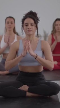 Dikey. Kadın eğitmen ve grup olarak yoga eğitmeni içeride egzersiz yapıyor. Sınıfta konsantre meditasyon yapan insanlar. Toplumda sağlıklı yaşam tarzı, sağlık ve günlük rutinler