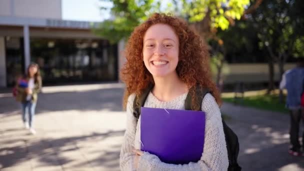 Seorang Siswa Muda Berambut Merah Tersenyum Melihat Kamera Memegang Folder — Stok Video