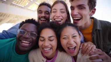 Çok ırklı gülüşen bir grup gencin portresi, akıllı telefonlarının ön kamerasına bakarak gülümsüyor ve selfie çekiyorlar. Z neslinin çeşitli arkadaşları dışarıda eğleniyor.