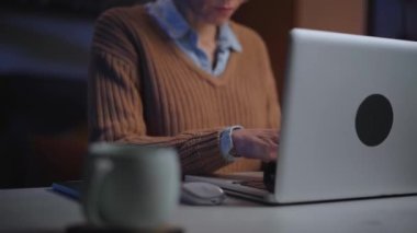 Akşamları evde dizüstü bilgisayar kullanan konsantre, beyaz bir kadın. Ciddi bir kadın bilgisayarda yazı yazıyor. Oturma odasında oturan insanlar. Çevrimiçi bilgi arayan olgun insanlar tıraş edildi