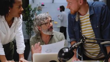 Modern ofis çeşitli iş arkadaşları erkek kıdemli liderle konuşarak iş stratejileri geliştirmek için toplantılar yapıyorlar. İş arkadaşları patronla konuşuyor. İnsanlar işlerini geliştirmek için fikirlerini paylaşıyorlar..