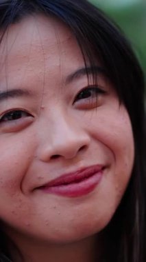 Dikey yakın plan Asyalı hoş bir bayan, güler yüzlü, dışarıdaki kameraya neşeli bir şekilde bakıyor. Nesiller z güzel Çinli kadın kahverengi gözlü ve siyah saçlı neşeli portre pozu veriyor.