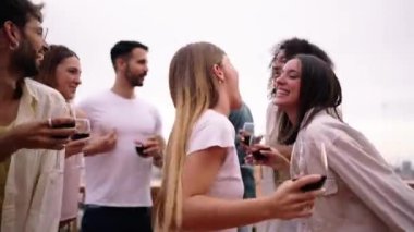 Güzel sarışın kadın, kameraya flörtöz bakıyor ve grupla dans ediyor. Heyecanlı arkadaşlar, kutlama için çatı katı partisinde kırmızı şarap kadehleriyle buluşuyorlar. İnsanlar tatilden hoşlanıyor