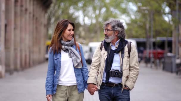 快乐的资深白人游客夫妇手牵着手在城市街道上互相望着 成熟的婚姻谈情说爱 享受浪漫的出游 积极的关系和春假 — 图库视频影像