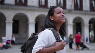 Gülümseyen genç bir Afro-Amerikalı kadın şehir meydanında yürüyor. Etrafına bakıp Avrupa 'nın mimarisine hayran olan güzel bir turist.