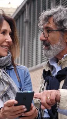 Dikey. Şehrin caddesinde konuşan ve cep telefonu kullanan olgun bir turist çifti. Yetişkin evliliği Avrupa 'da tatilde olan bir hücreyi kontrol ediyor. Emekli insanlar ve zaman yolculuğu.