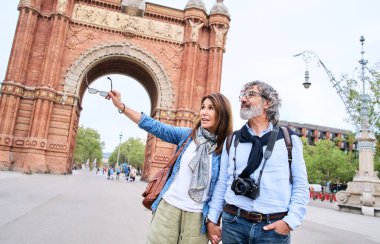Barselona 'da tatillerinin tadını çıkaran olgun turist çifti. Kadın şehir meydanında kocasının elini tutan bir şeyi işaret ediyor. Tatil turizmindeki mutlu orta yaşlı insanlar