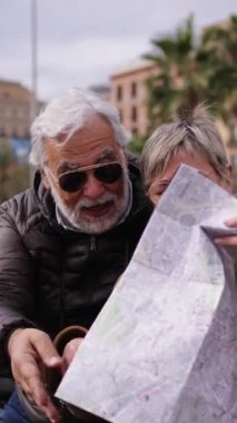 Dikey yaşlı Kafkasyalı çift ellerinde harita tutarak turistlerin ilgisini çeken yerlere bakıyorlar ve konuşuyorlar. Karı koca şehir bankında oturmuş emeklilik tatilinin keyfini çıkarıyorlar.