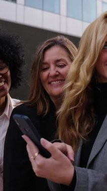 Dikey. Neşeli bir grup çok ırklı kadın, bir cep telefonu kullanarak bir heyecan ya da sürpriz anlarını paylaştılar. Video, ekrana birlikte bakarken ifadeleri ve tepkileri yakalar