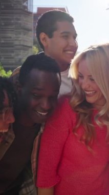 Genç Avrupalı öğrenci arkadaşlarla birlikte eğlenen ve dışarıda kucaklaşan bir grubun dikey fotoğrafı. Birleşmiş Nesiller Z insanları, şehir sokaklarında kucaklaşarak topluluk içinde zaman geçiriyorlar..