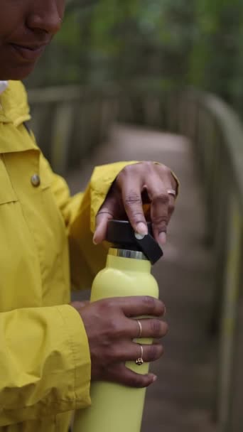 Vertical Video Young Latin Woman Wearing Yellow Rain Jacket Drinking — Stock Video