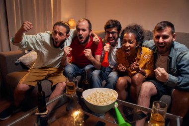 Futbol hayranları, Stylish Loft Apartment 'da bir kanepede rahatlar, Evde Spor Maçı izlerler. Heyecanlı Genç Arkadaşlar En İyi Futbolcuları İçin Tezahürat Yapıyor, Oyuncuların Gol Sayısını Kutluyor