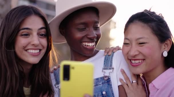 Tre Unge Multiraciale Kvinder Ser Overrasket Gul Mobiltelefon Sammen Udendørs – Stock-video