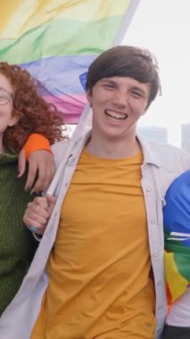 Dikey. Gurup genç ve neşeli arkadaşları eşcinsellerin geçit töreninde birlikte dolaşıyorlar. LGBT topluluğu kucaklaşarak dışarıdaki kameraya gülümsüyor. Z jenerasyonu ve cinsel özgürlük.. 