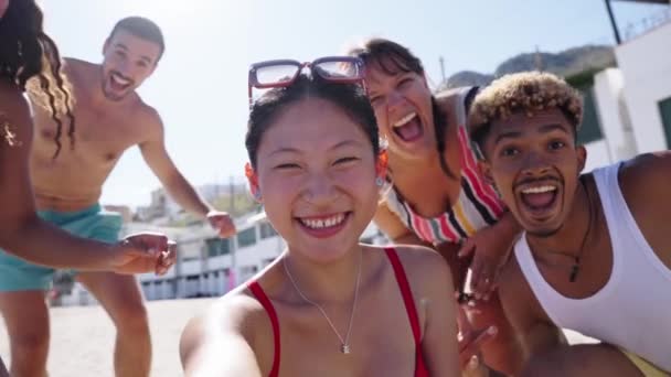 ビーチでZ陽性の興奮するグループの喜びの多種多様な若者のソーシャルメディアのセルフィービデオ 友人たちはカメラに手を振って笑い 一緒に楽しんでいました 夏休みの旅行を楽しんでいる人 — ストック動画