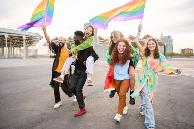 Genç LGBT cemaati neşeli çeşitli arkadaşlar eşcinsellerin geçit töreninde birlikte dolaşıyorlar. Mutlu gökkuşağı renkli insanlar gülümsemeyi seviyorlar, kucaklaşmayı dışarıda yürümeyi. Z jenerasyonu ve cinsel özgürlük.. 