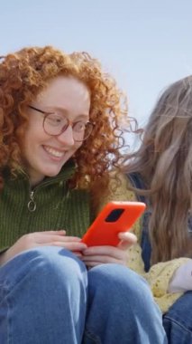 Dikey. Geniş bir grup neşeli genç LGBT topluluğu açık havada cep telefonu kullanarak kuyrukta bekliyor. Gülümseyen arkadaşlar eşcinsellerin gurur gününü kutluyorlar. Z nesli sosyal medyaya bağımlı