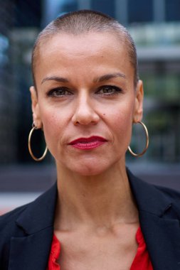 İş yerinin dışında duran, modern tıraşlı takım elbiseli, kameralı beyaz iş kadınının dikey portresi. Güçlü, başarılı kadın ciddi ifadesi