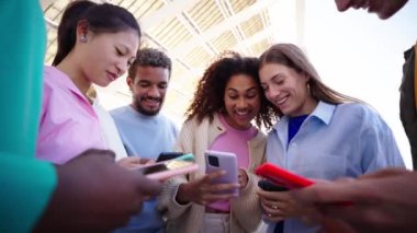 Bir grup çok ırklı genç, cep telefonlarıyla gülerek ve akıllı telefonlara bakarak daireler çiziyor. Komik videolar izliyorlar. Neşeli arkadaşlar birlikte dışarıda eğleniyorlar. Z jenerasyonunun iletişim ve bağımlılığı 